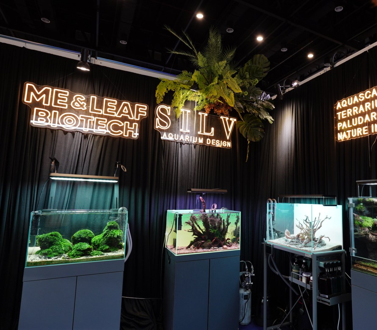 SILV Aquarium Design expo booth with neon signage and planted display tanks